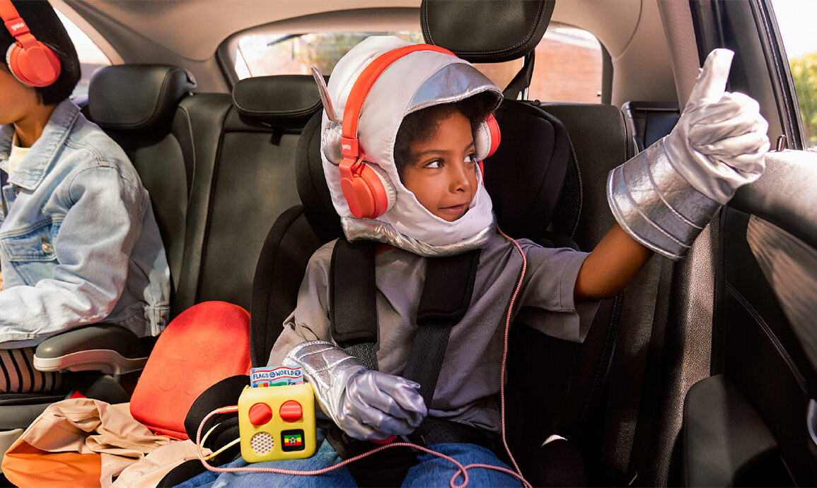 Un enfant écoute son Yoto Mini avec un casque sur la banquette arrière d'une voiture