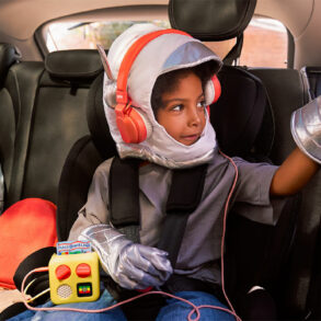 Un enfant écoute son Yoto Mini avec un casque sur la banquette arrière d'une voiture