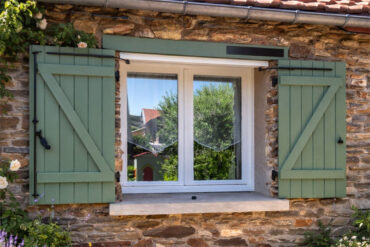 Motorisation solaire SLID'UP WINEO installée sur des volets battants verts d'une maison de campagne
