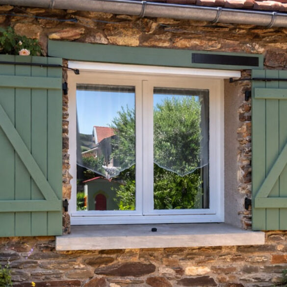 Motorisation solaire SLID'UP WINEO installée sur des volets battants verts d'une maison de campagne